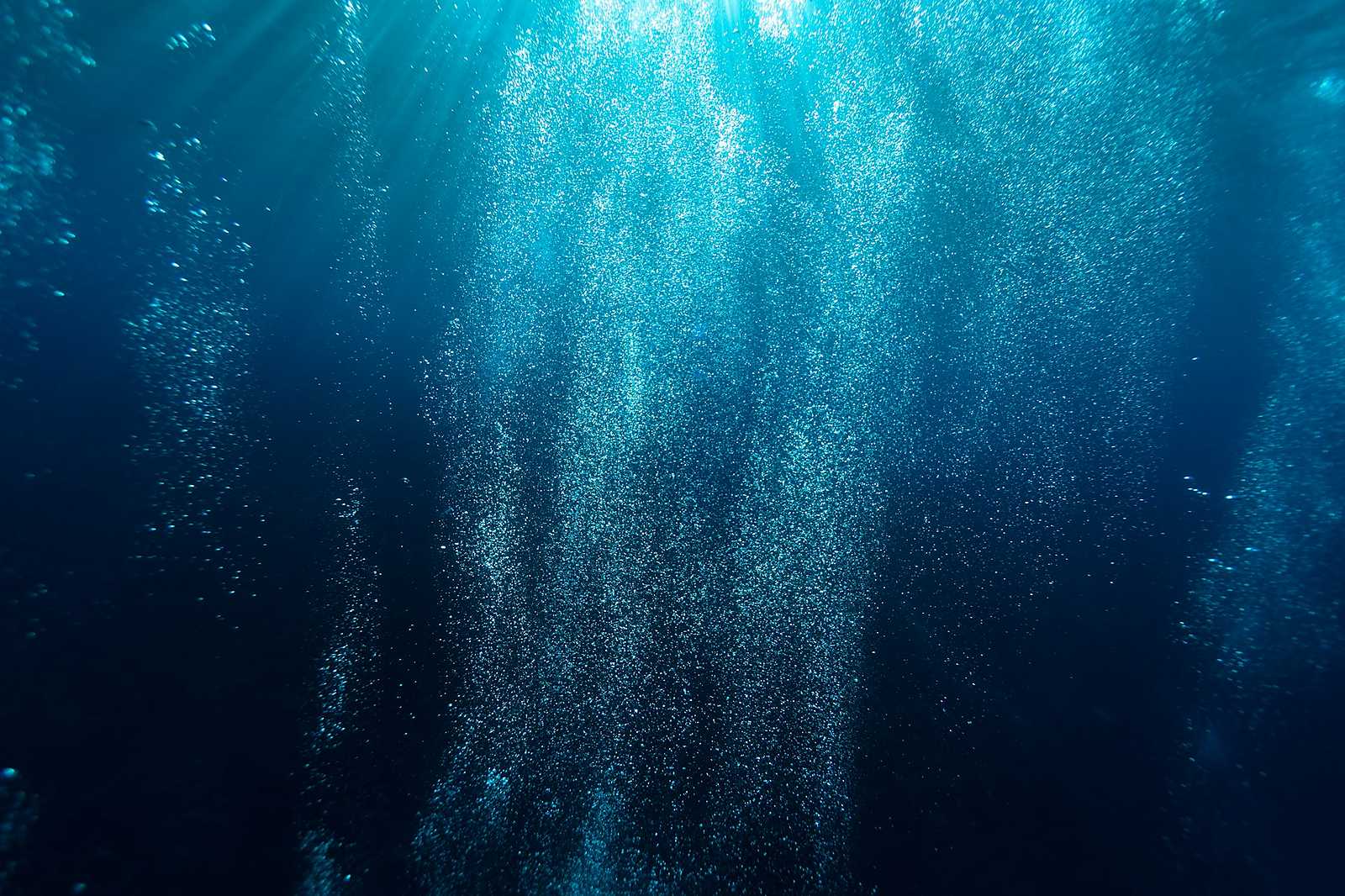 Scuba diver descending through sunlit blue water